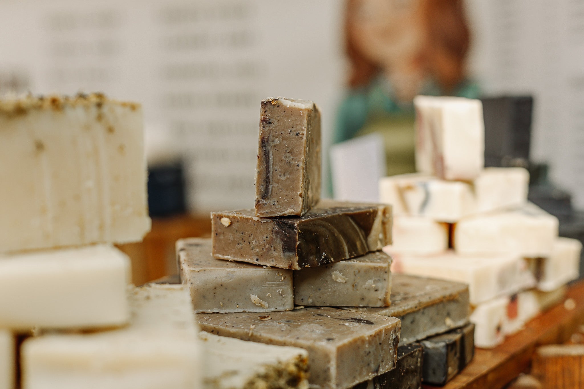 Stacks of handmade soap bars on a wooden surface with a blurred background