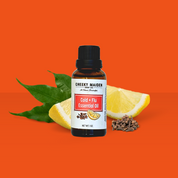 Bottle of Cheeky Maider Cold + Flu essential oil with lemon slices and leaves on an orange background