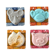 Four animal-shaped bath bombs in their packaging on a white background