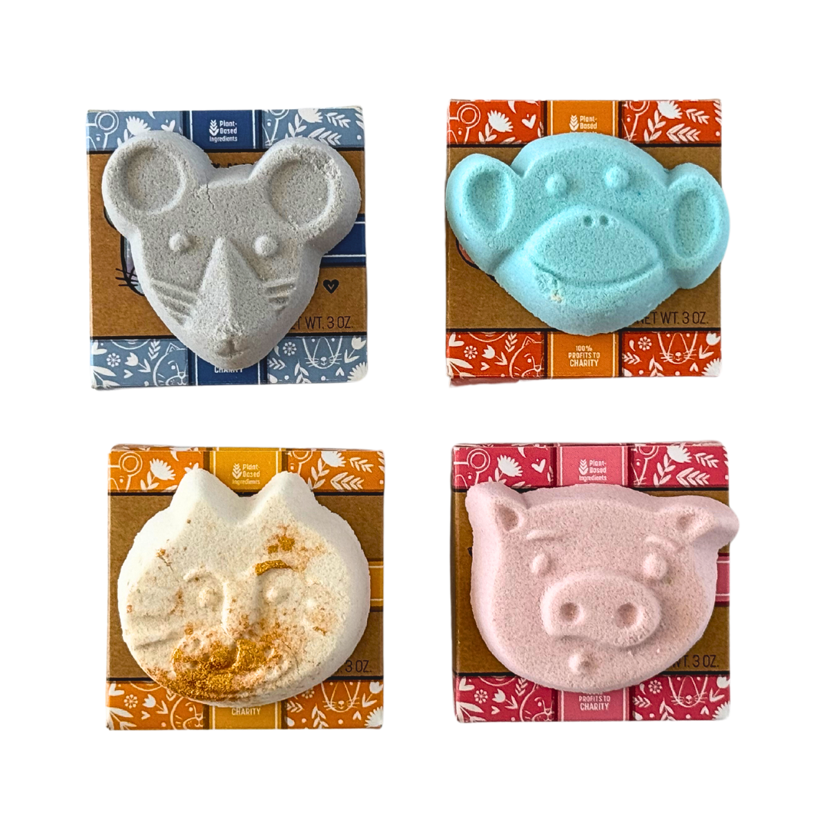 Four animal-shaped bath bombs in their packaging on a white background