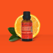 Bottle of Orange essential oil with an orange and leaf on an orange background