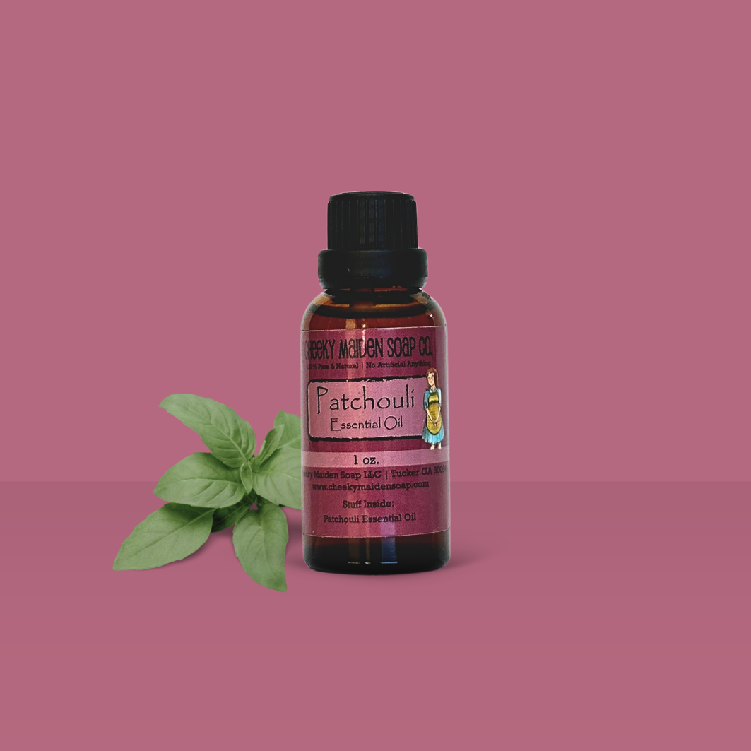 Bottle of Patchouli essential oil with a green leaf on a pink background