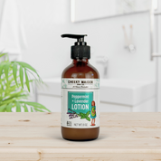 Bottle of Cheeky Maiden Peppermint + Lavender Lotion on a wooden surface with a blurred background