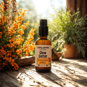 Bottle of 'Glow Getter' sea buckthorn oil on a wooden surface with plants in the background