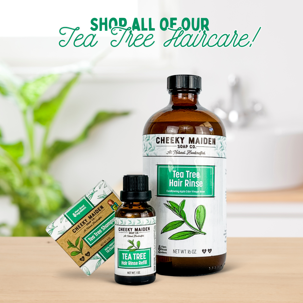 Cheeky Maiden Tea Tree hair care products on a wooden surface with a blurred plant background.